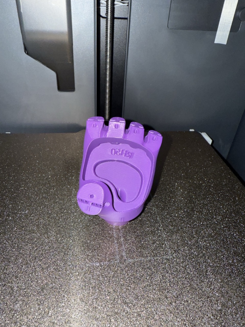 Purple hand base printing on the 3D printer bed